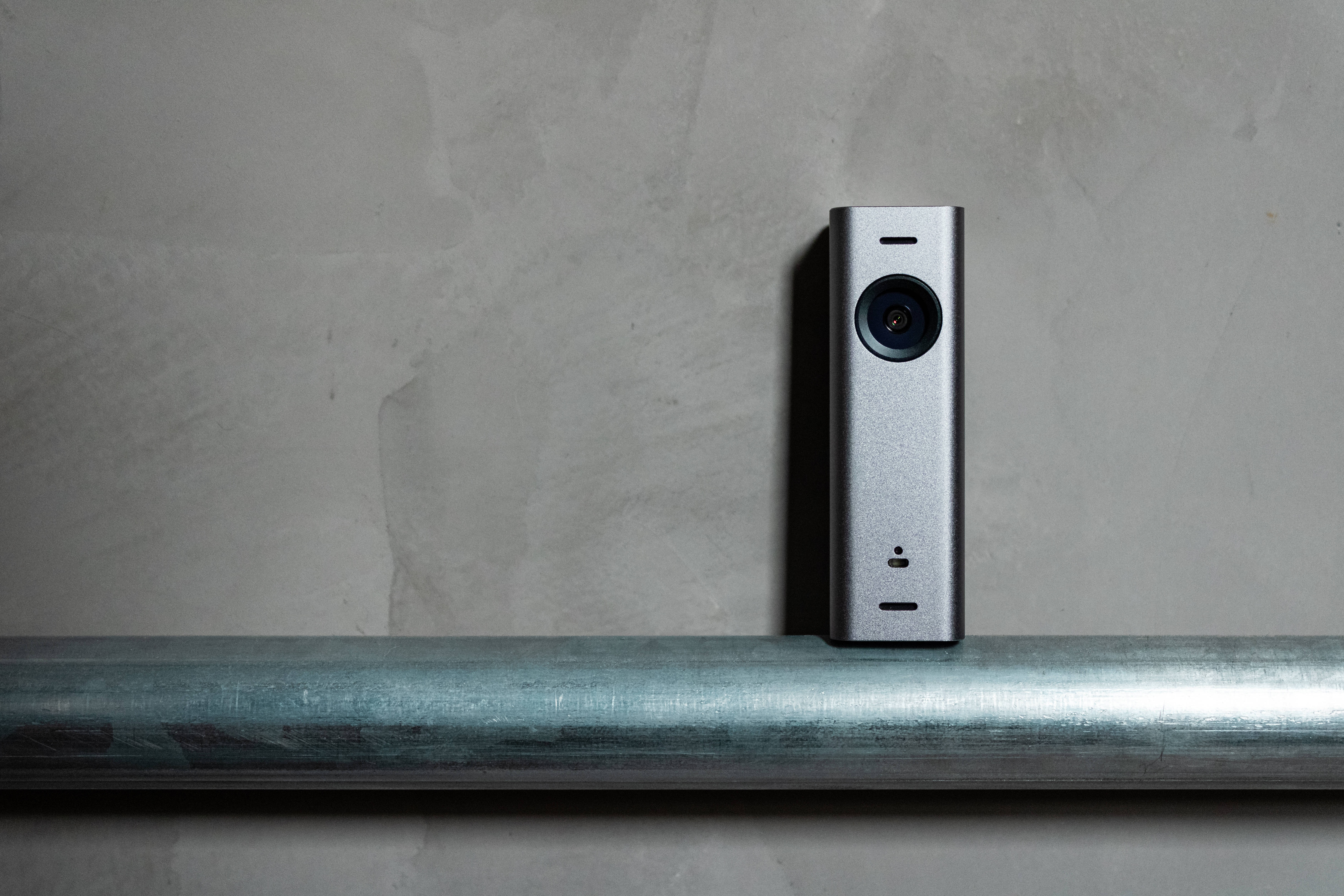 rectangular tall silver webcam, brushed metal pipe, textured concrete wall, 5K Desktop Wallpaper