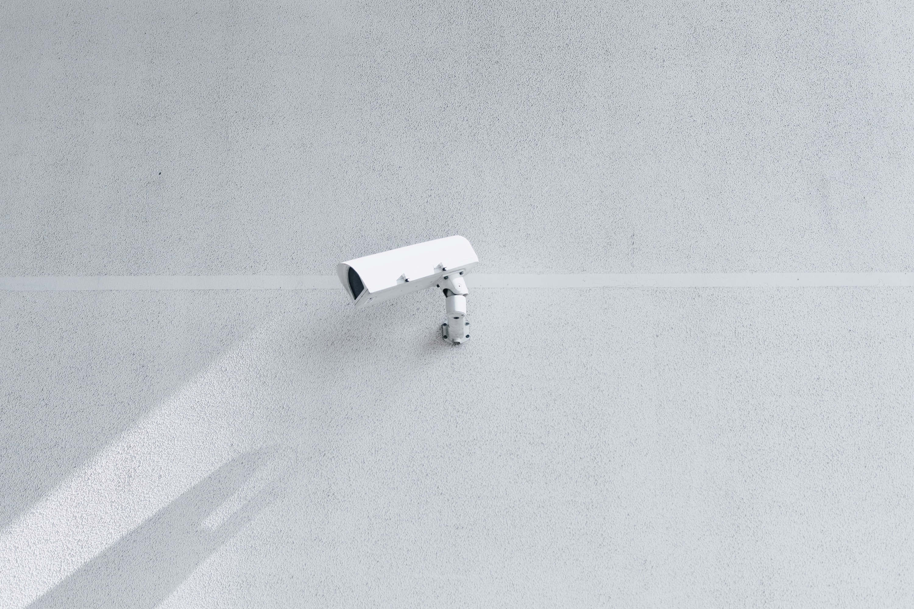white wireless cctv security camera, textured gray wall, bright daylight, 2K Desktop Wallpaper