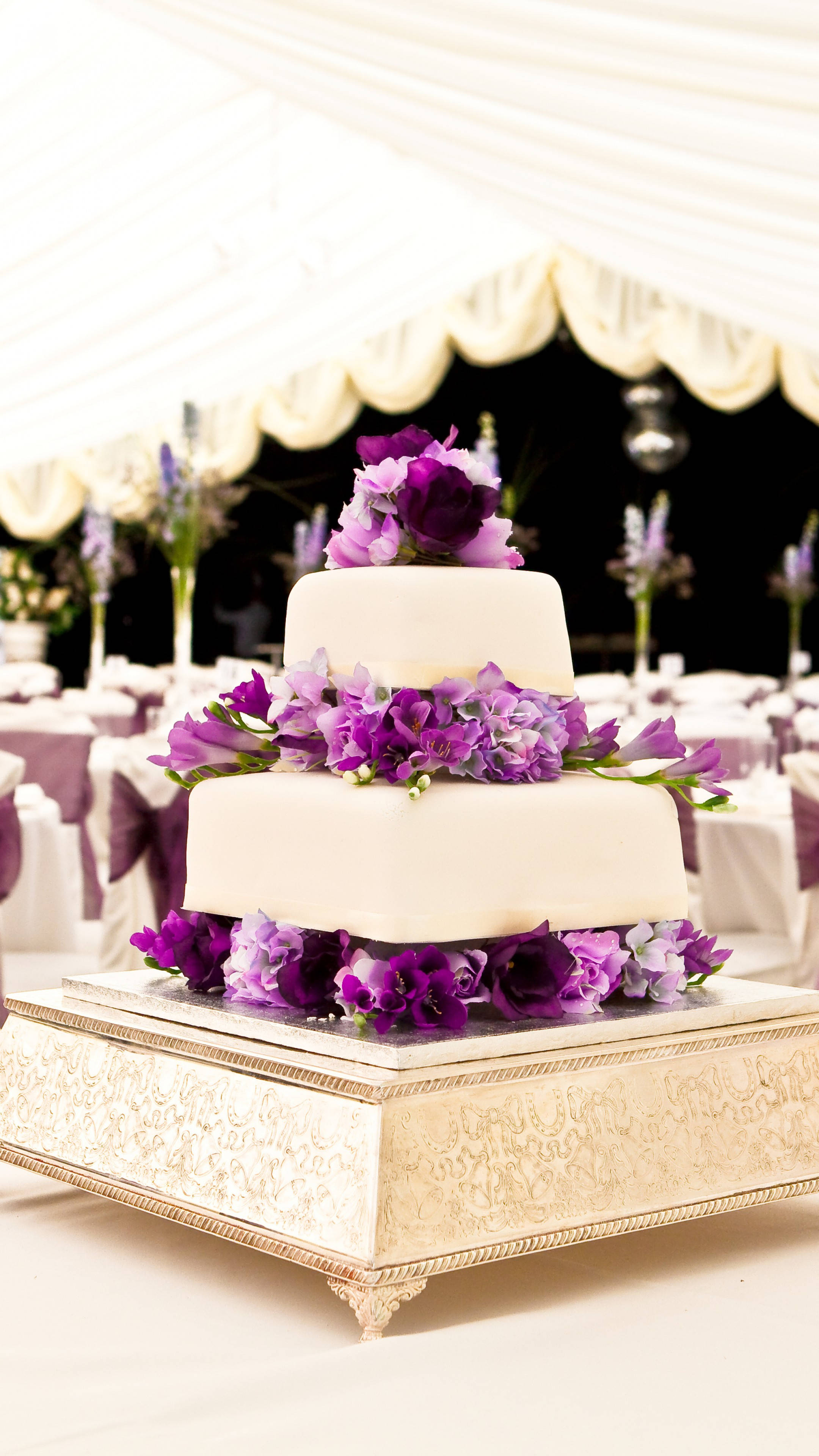 two-tiered white wedding cake, lush purple flowers, ornate silver stand, 4K Phone Wallpaper