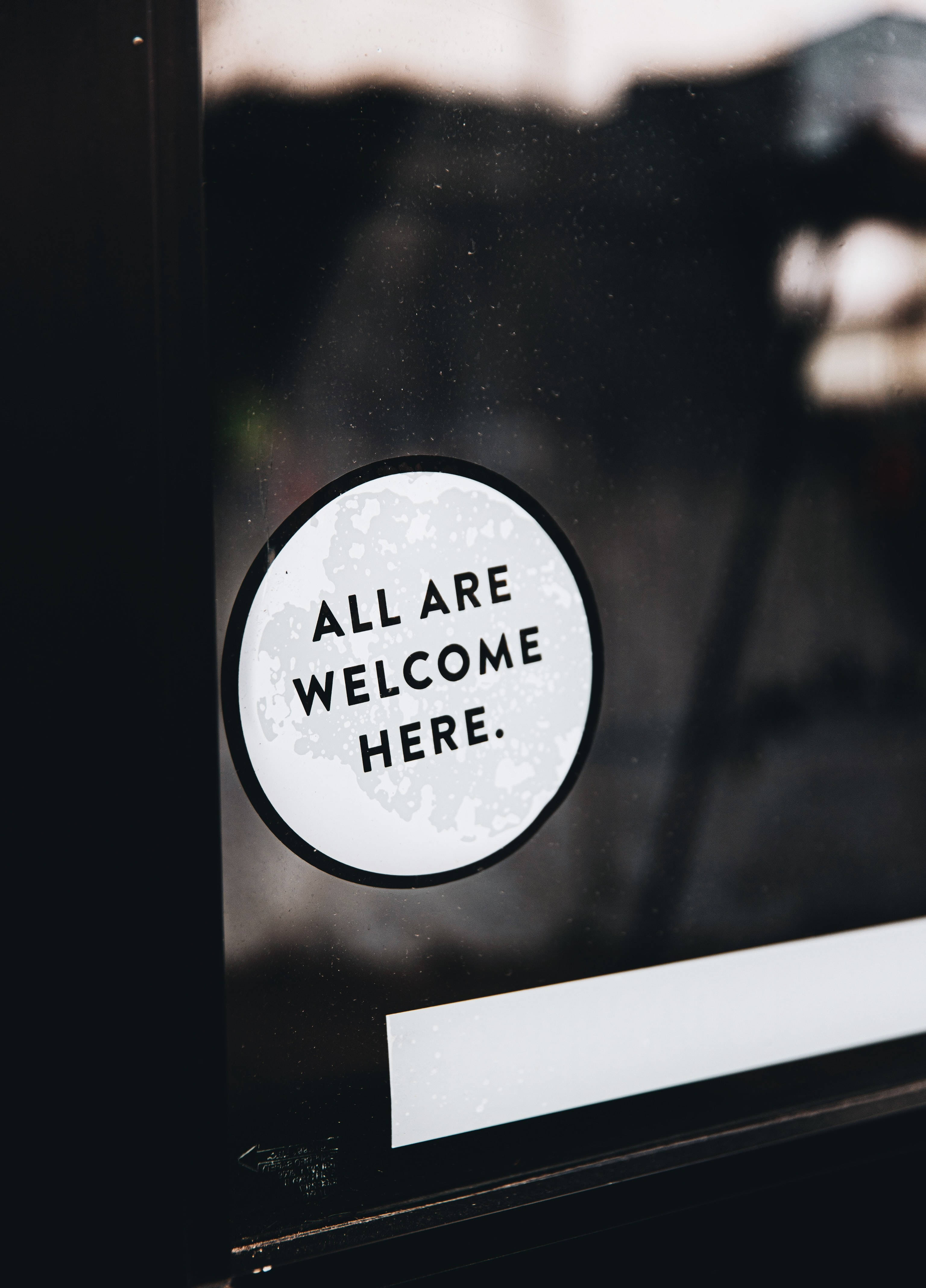ALL ARE WELCOME HERE, white circular sticker, black text, 4K Phone Wallpaper