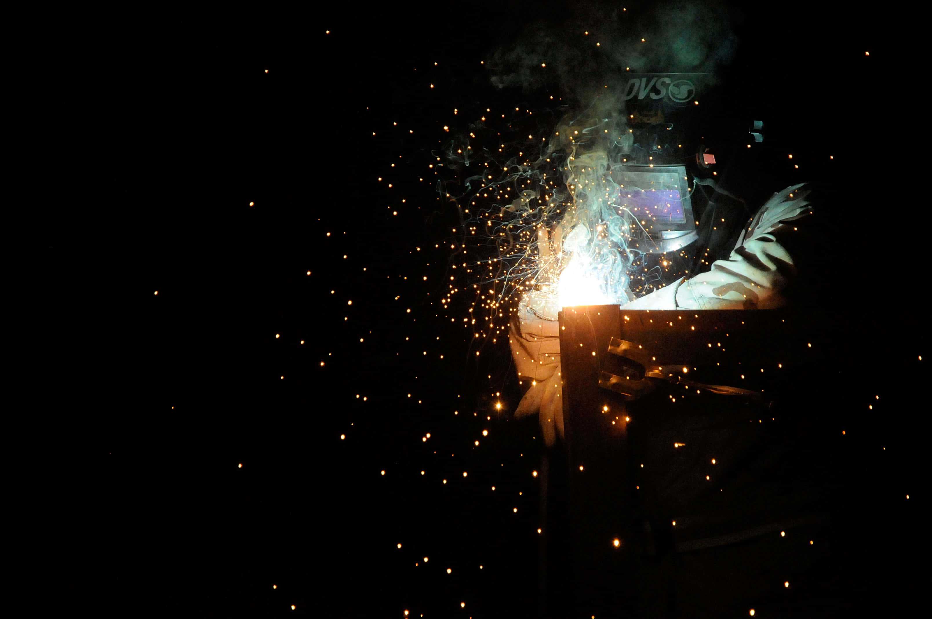 welder, dark gear, bright orange sparks, 2K Desktop Wallpaper