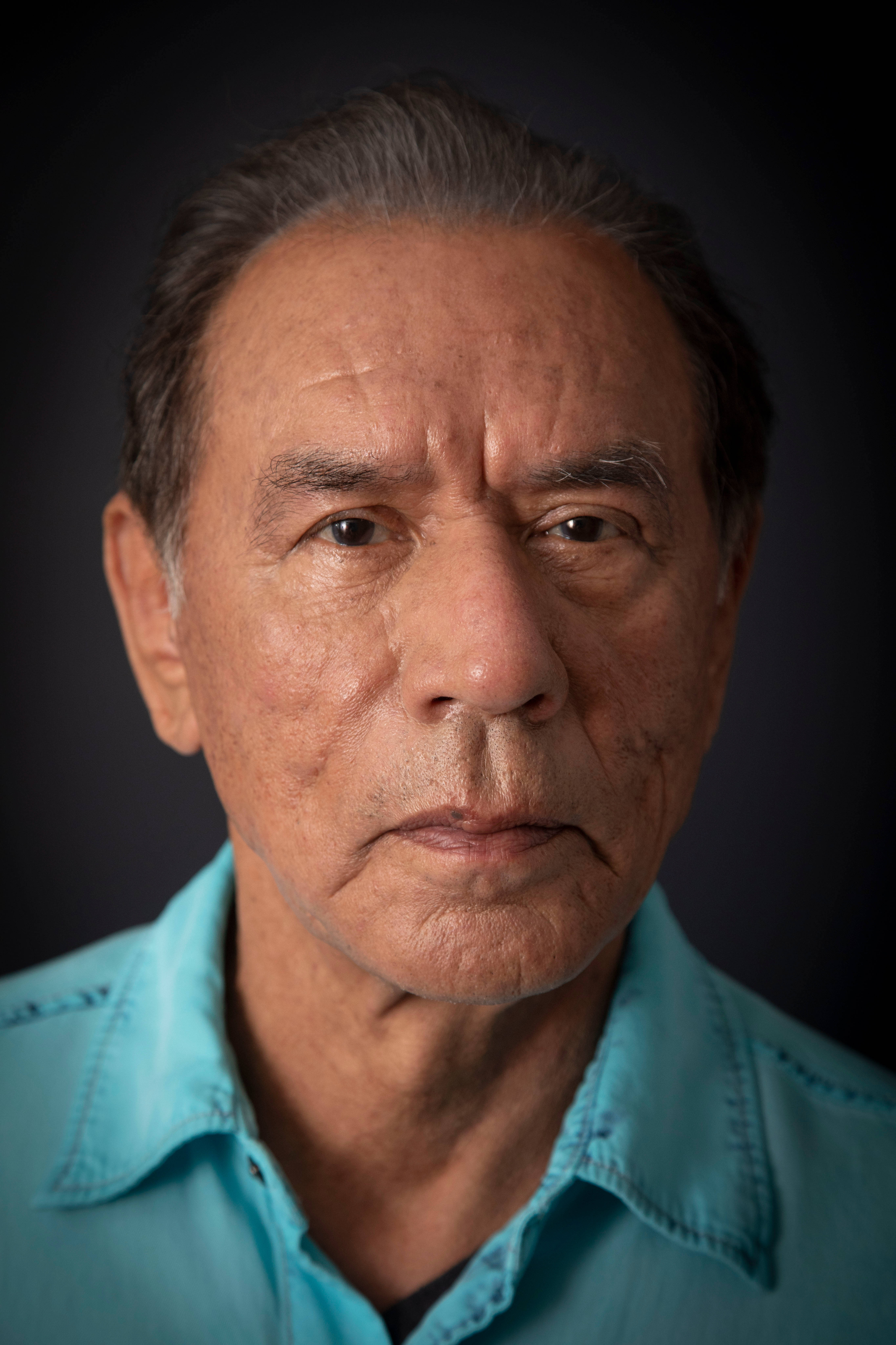 Wes Studi, turquoise shirt, dark background, 5K Phone Wallpaper