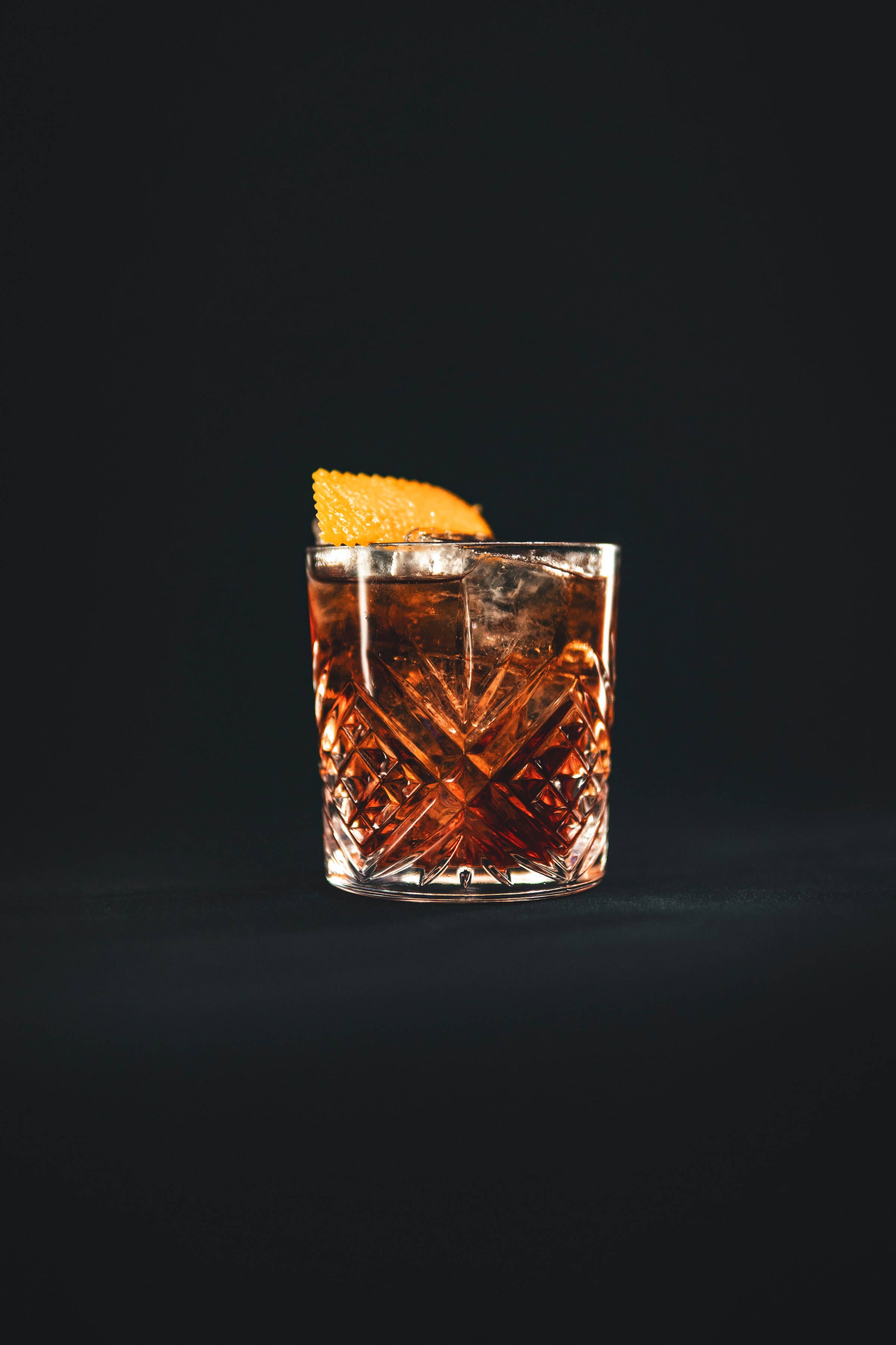small glass of bourbon whiskey cocktail, amber cocktail, ice garnished with orange peel, 2K Phone Wallpaper