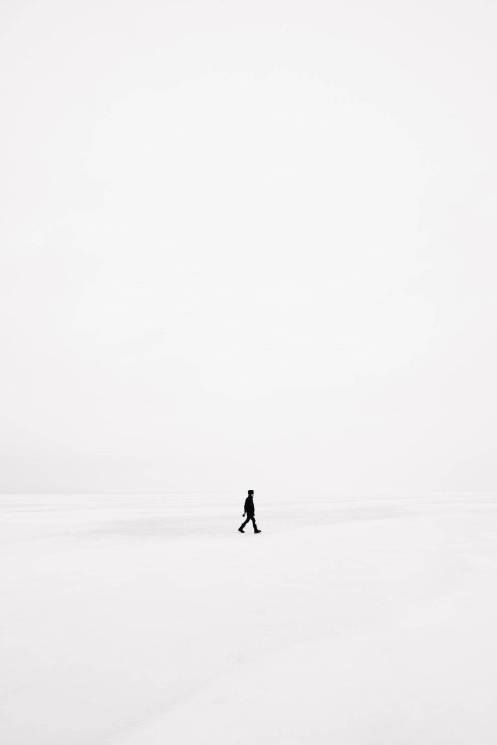 minimalist walking silhouette, white snowy plain, pale gray sky, HD Phone Wallpaper