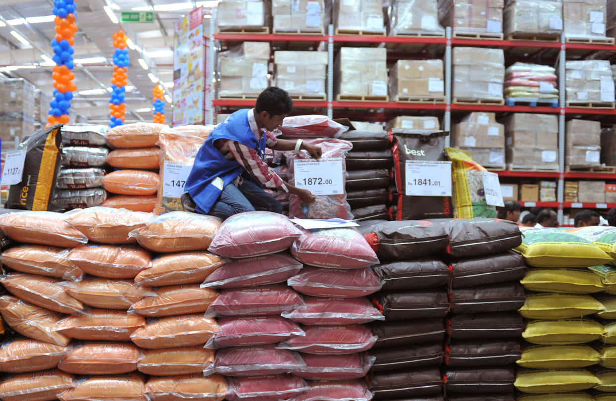 blue vest, towering stacks of colorful sacks, brightly lit warehouse, SD Desktop Wallpaper