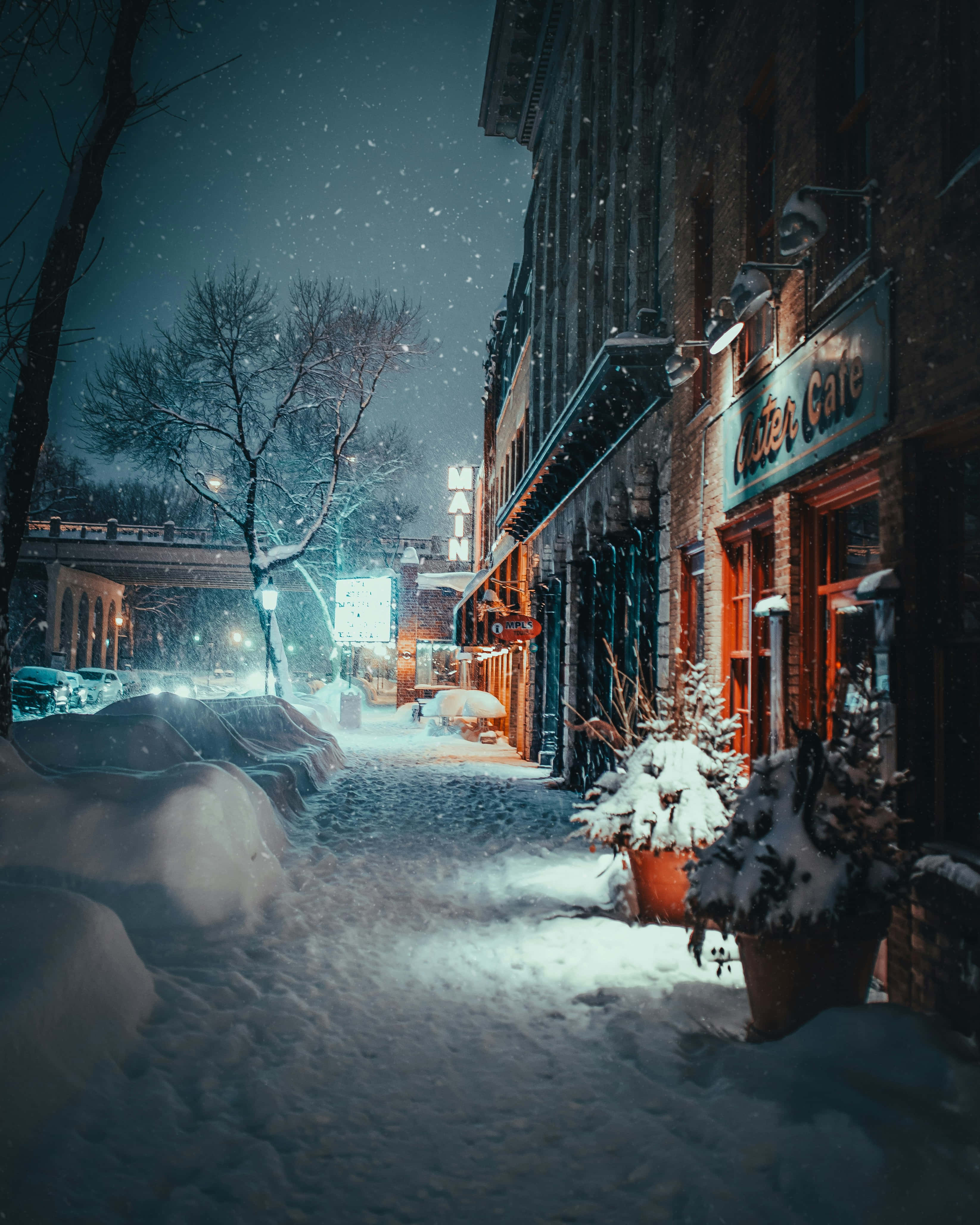 snowy evening cafe scene, warm lights, dark brick buildings, 4K Phone Wallpaper