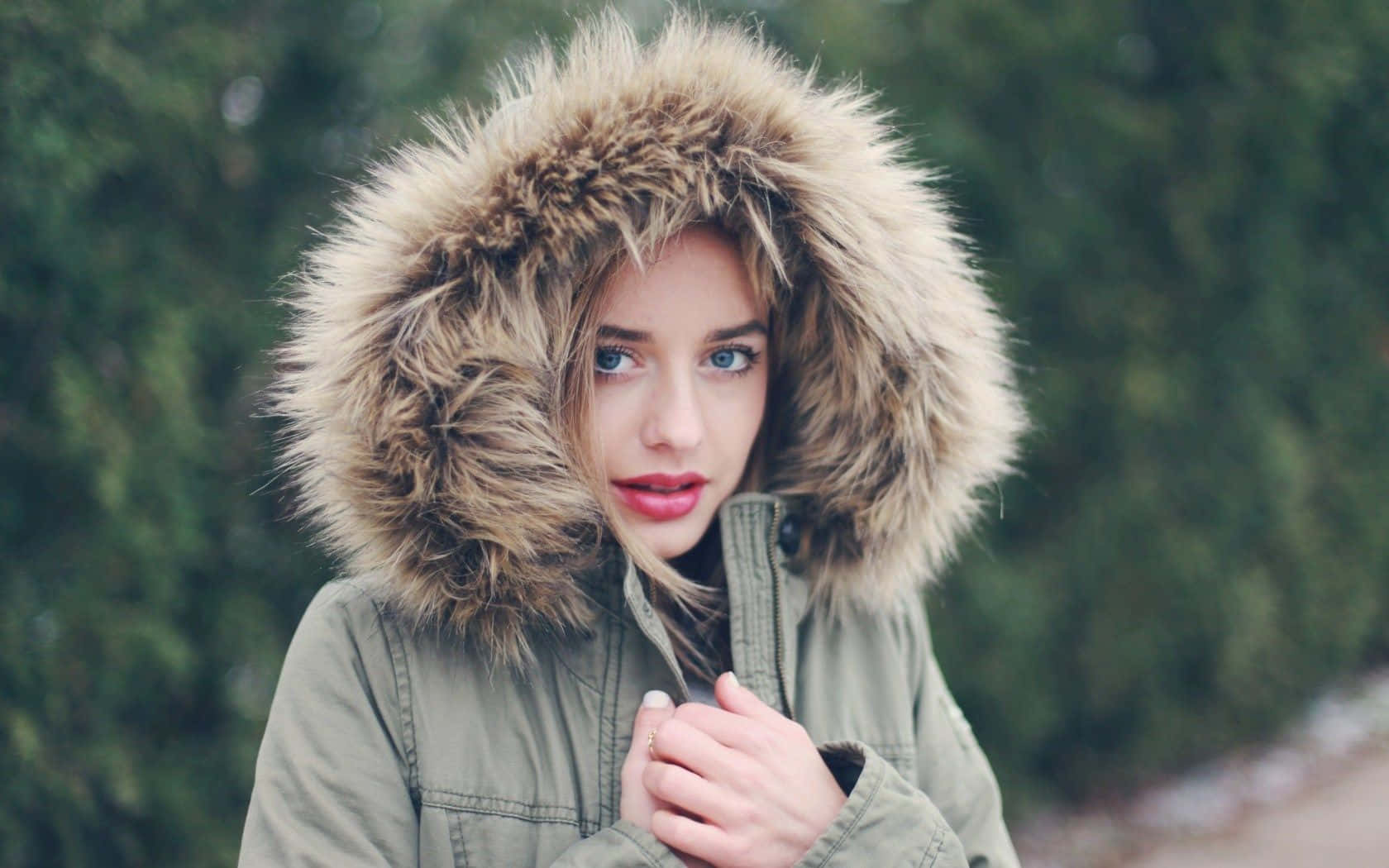 green parka, voluminous fur-lined hood, blurred forest backdrop, HD Desktop Wallpaper