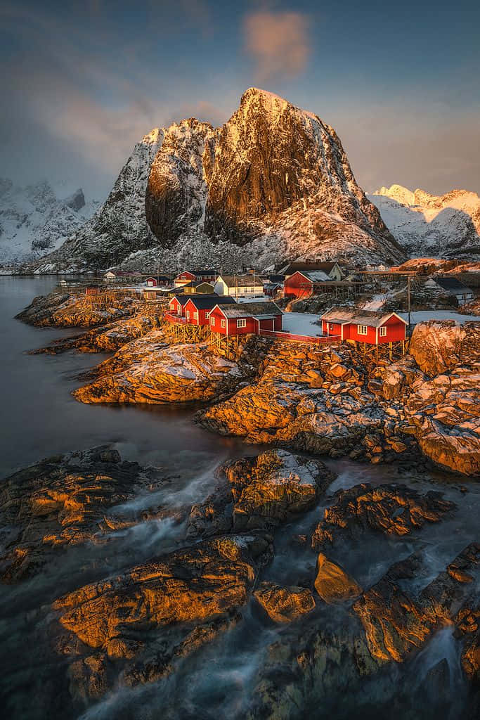 Red wooden cabins, snowy rocky shores, towering mountain, SD Phone Wallpaper