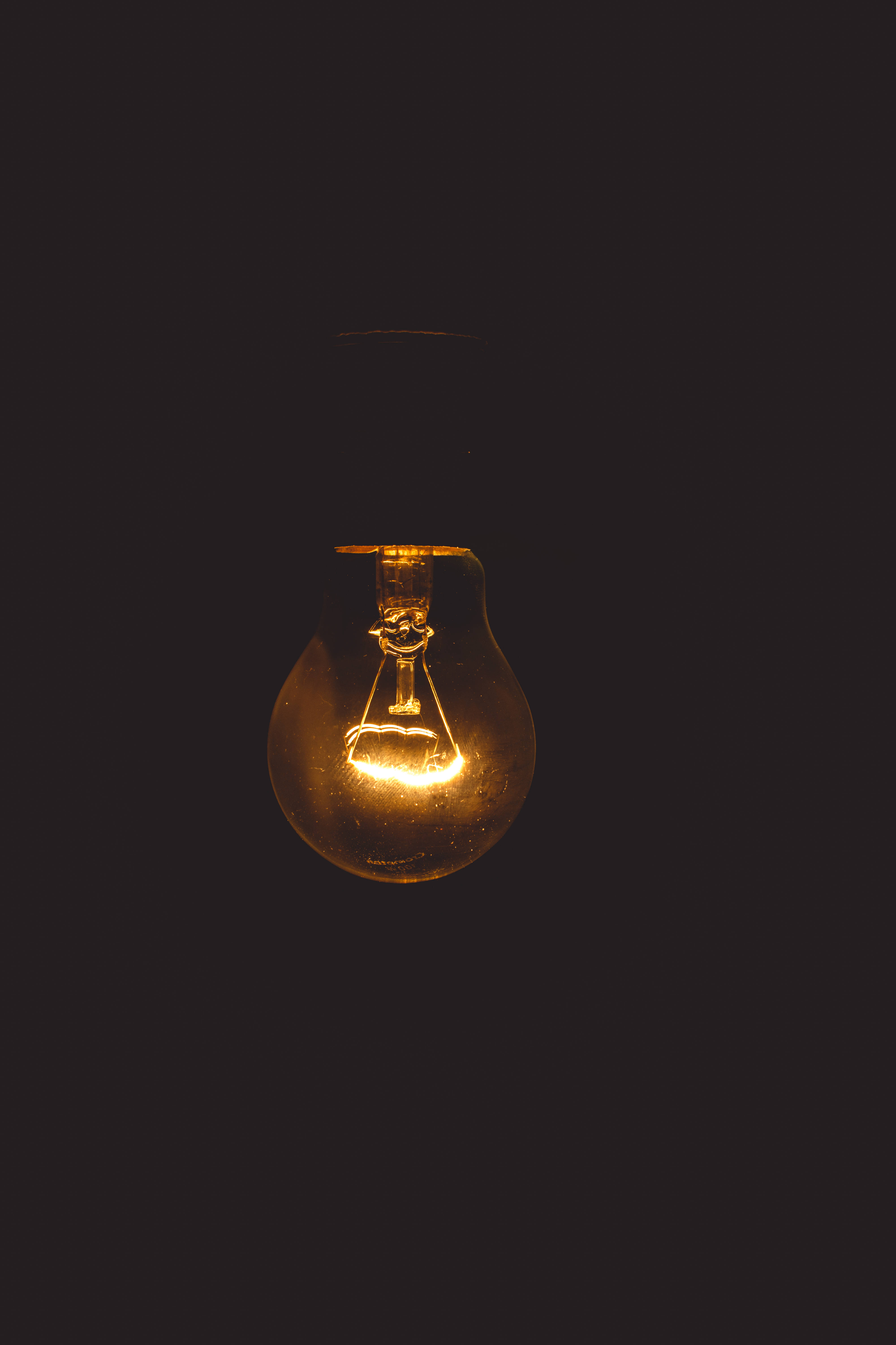 incandescent bulb, warm light, deep black background, 5K Phone Wallpaper