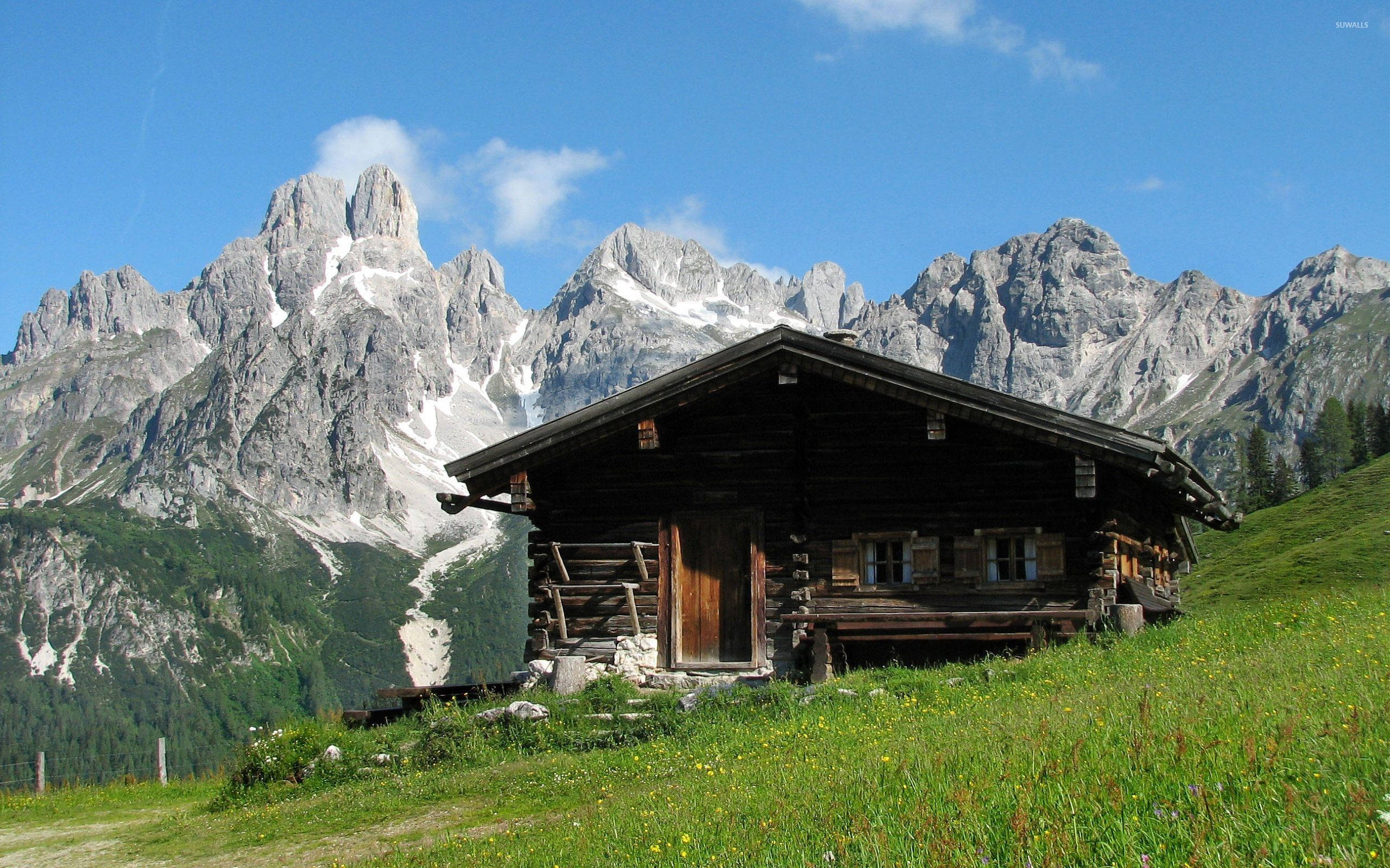 wooden cabin, snow-dusted mountains, sunlit green hillside, 2K Desktop Wallpaper