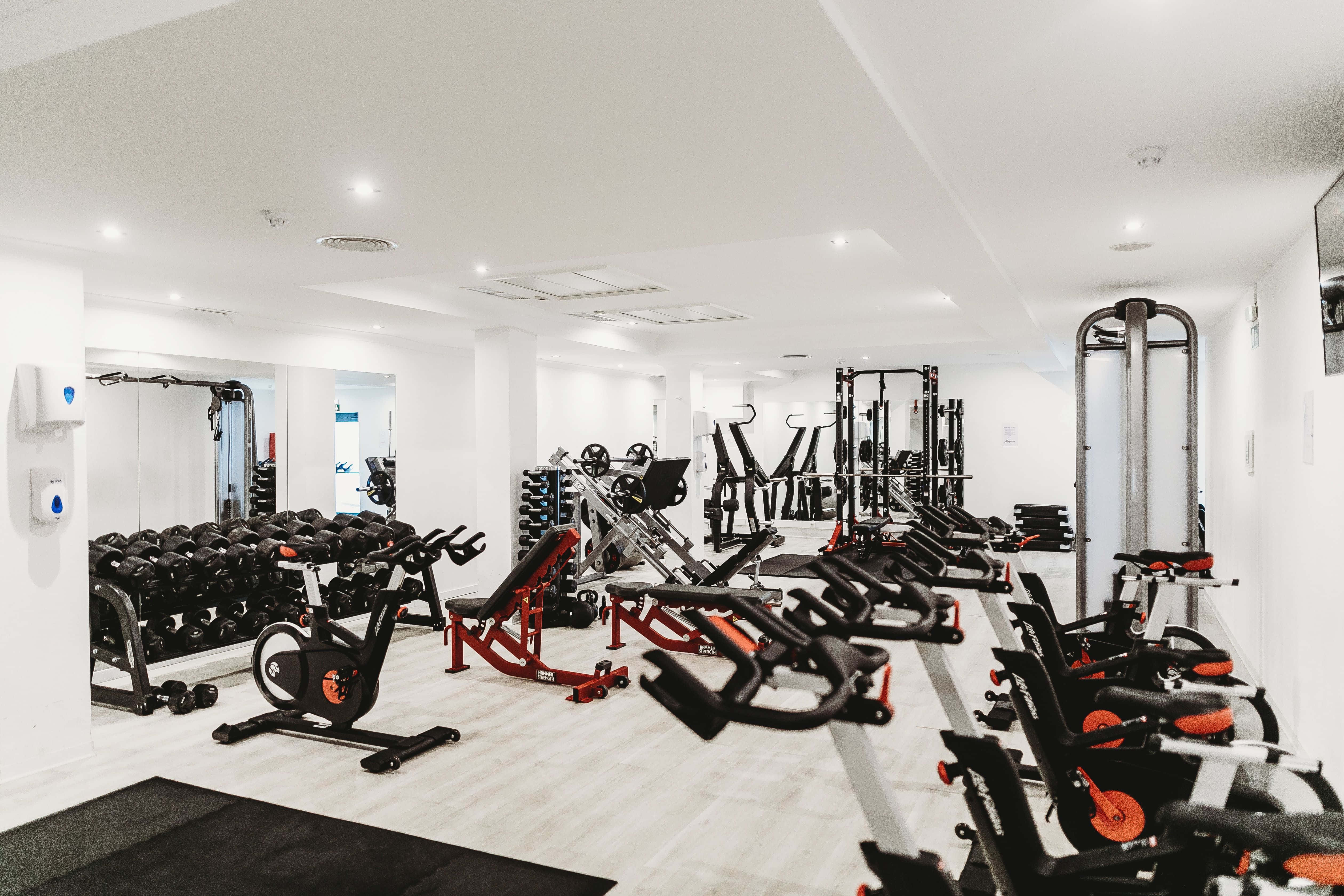 modern gym, black and orange exercise bikes, weight machines, 4K Desktop Wallpaper