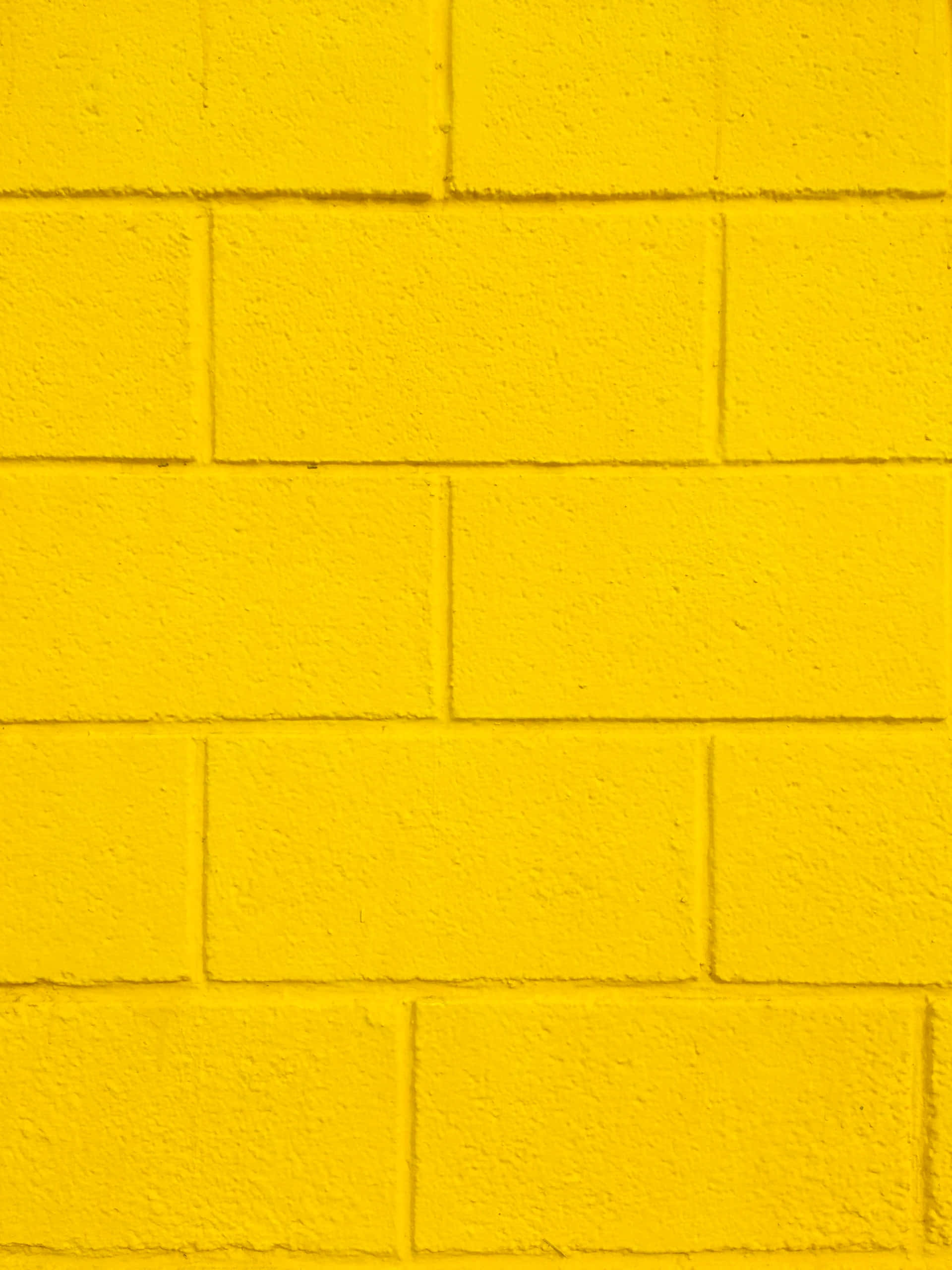 yellow painted brick wall, textured surface, visible mortar lines, 2K Phone Wallpaper
