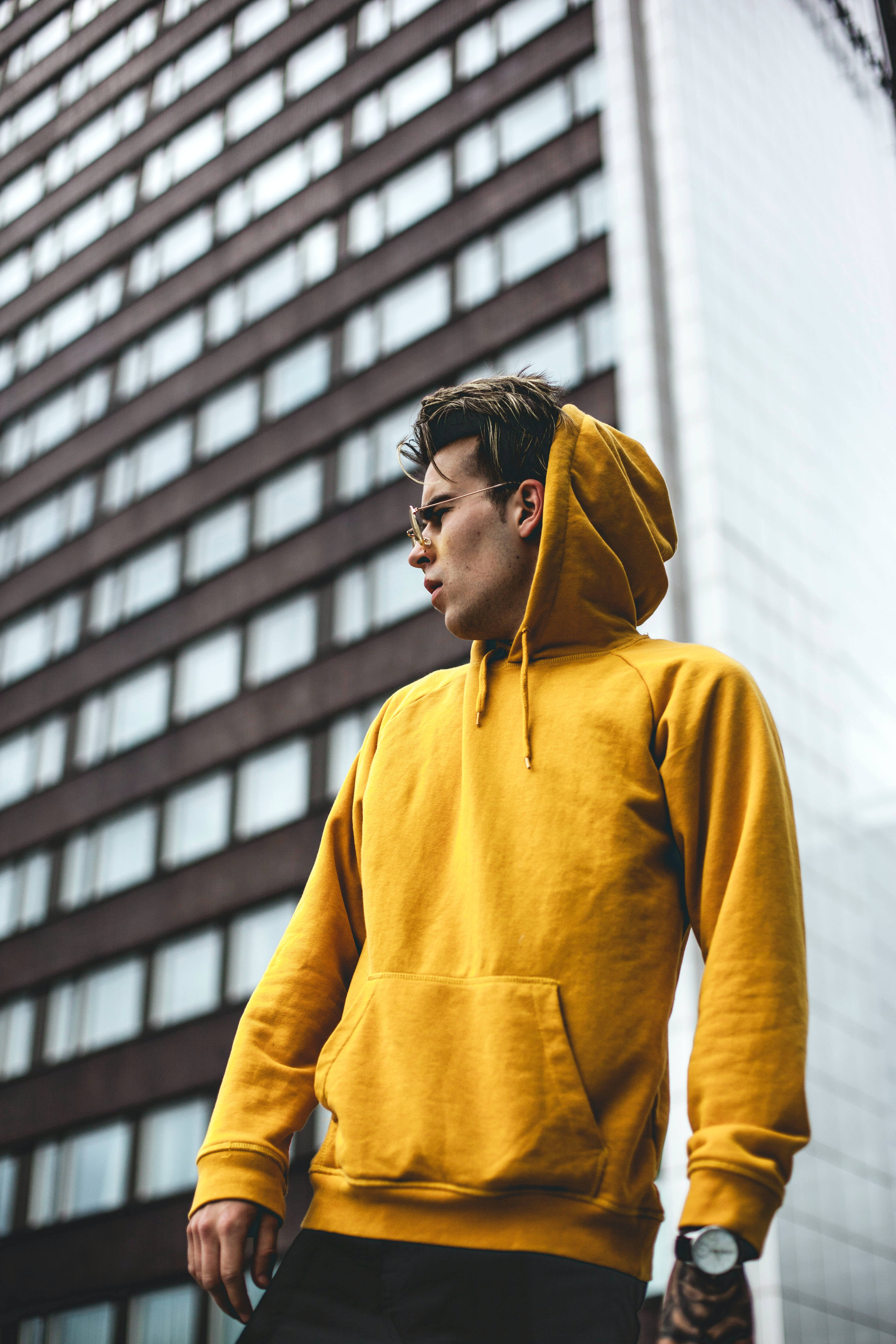 mustard yellow hoodie, glasses, modern city building facade, 5K Phone Wallpaper