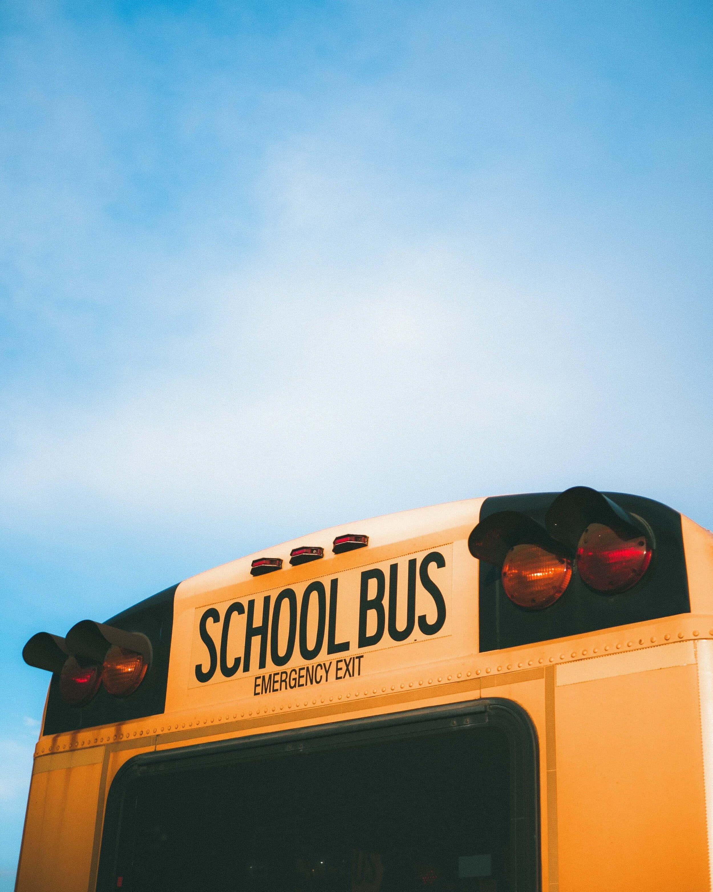 yellow school bus, emergency exit text, bright blue sky, 2K Phone Wallpaper
