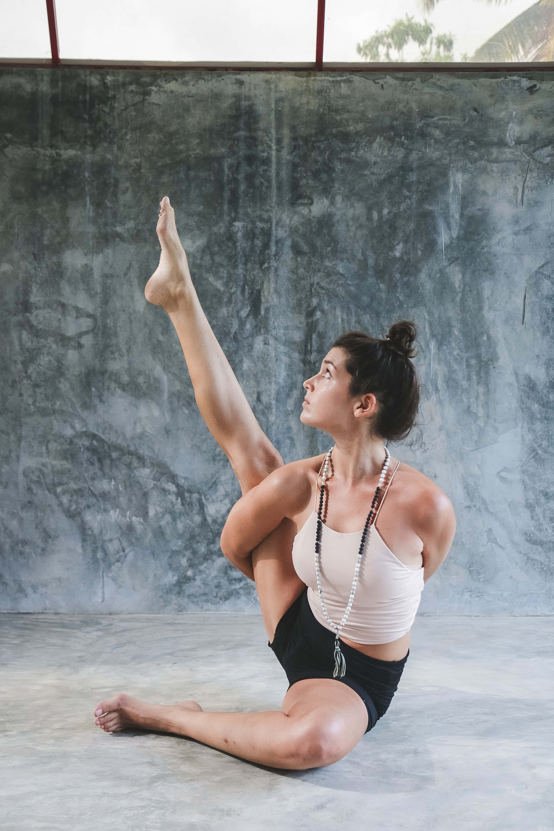 wide-legged yoga pose, textured gray concrete wall, minimalist studio, 2K Phone Wallpaper