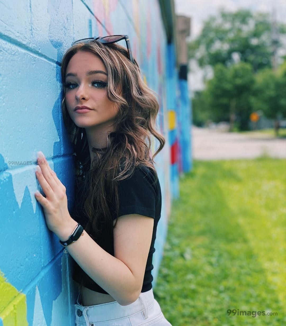 Zoe Laverne, vibrant blue graffiti wall, sunlit outdoor setting, SD Phone Wallpaper