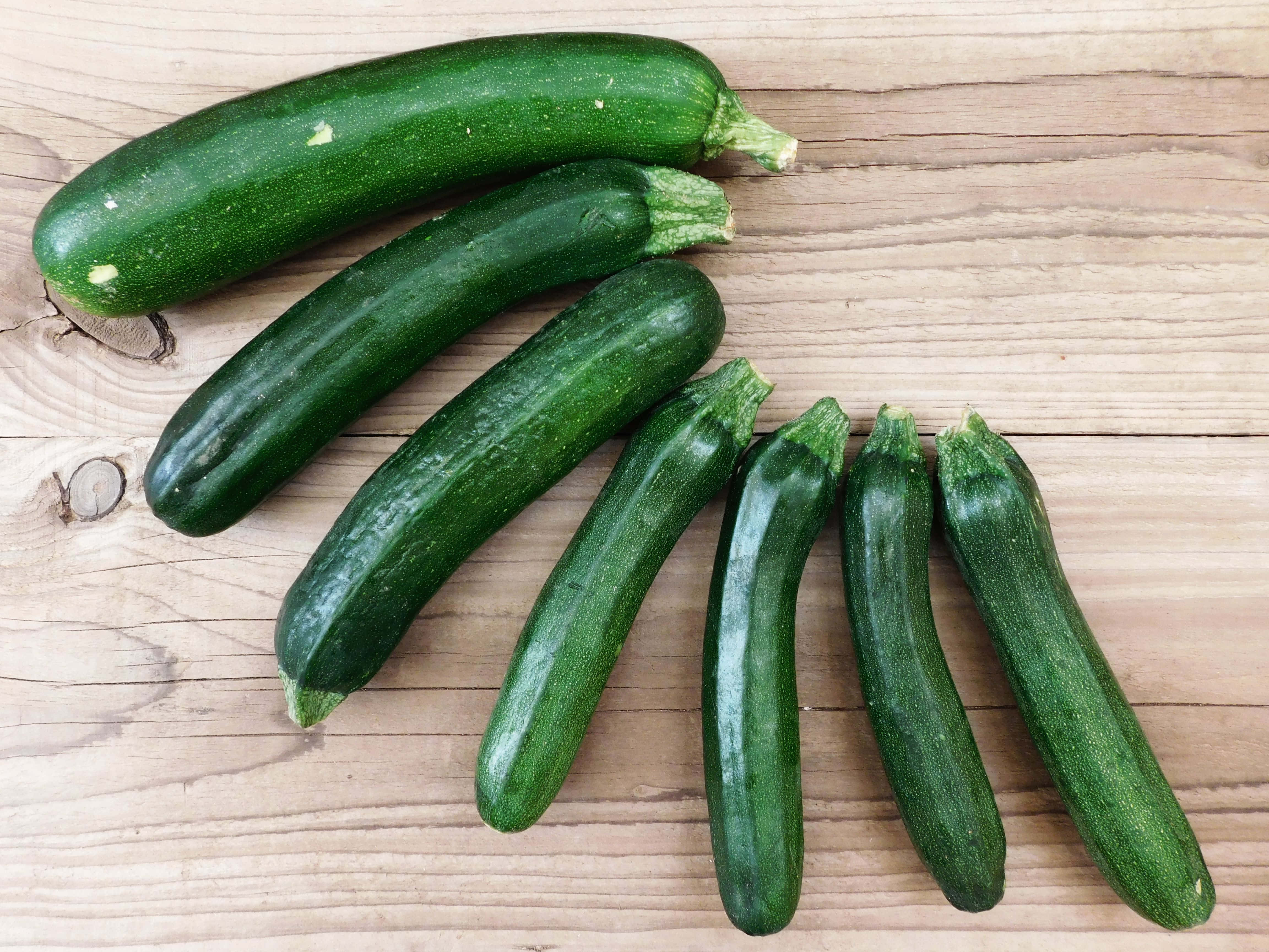 zucchinis, light wooden surface, visible grain, 4K Desktop Wallpaper